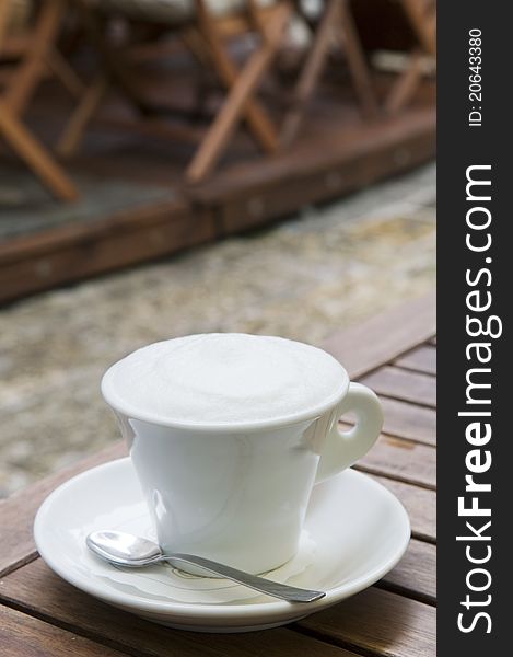 Cappuccino coffee cup outdoor in the street cafe over blur background