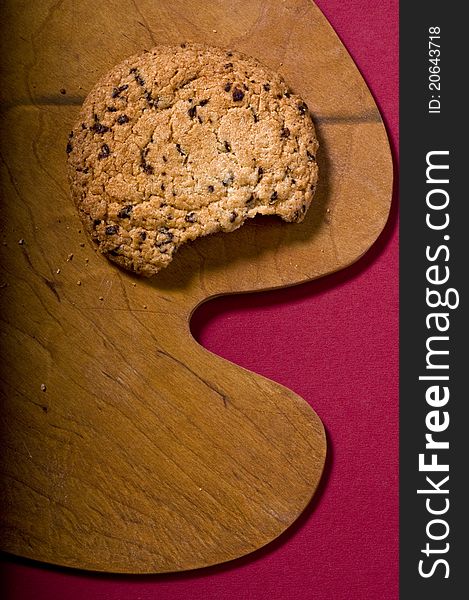 Chocolate cookie over on a cutting board over color background