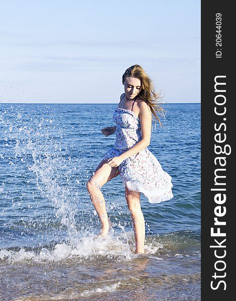 Young lady jumping with splash and smiling in the sea in sunlight. Young lady jumping with splash and smiling in the sea in sunlight