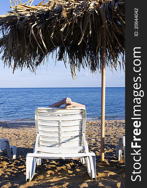 Young woman lying in the deck-chair on the beach in front of the sea