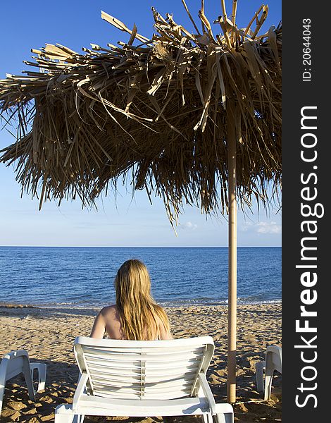 Young woman lying in the deck-chair in front of the sea