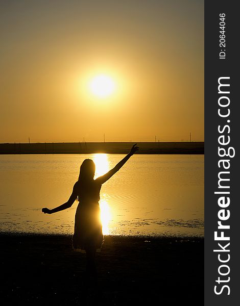 Silhouette of the dancing girl with sunset on the background