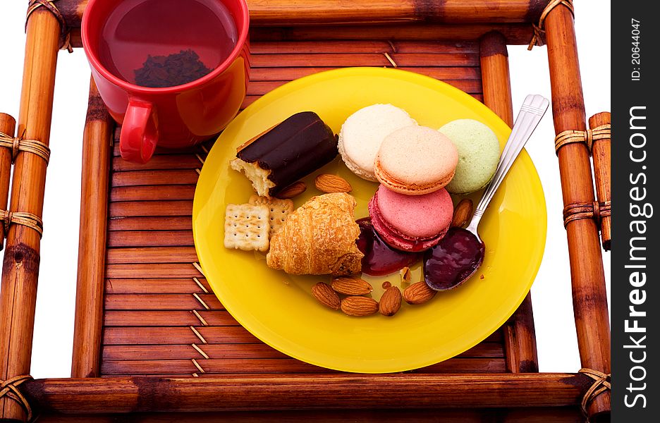 Breakfast with macaroons, croissant, eclair and almonds on the wooden tray. Breakfast with macaroons, croissant, eclair and almonds on the wooden tray