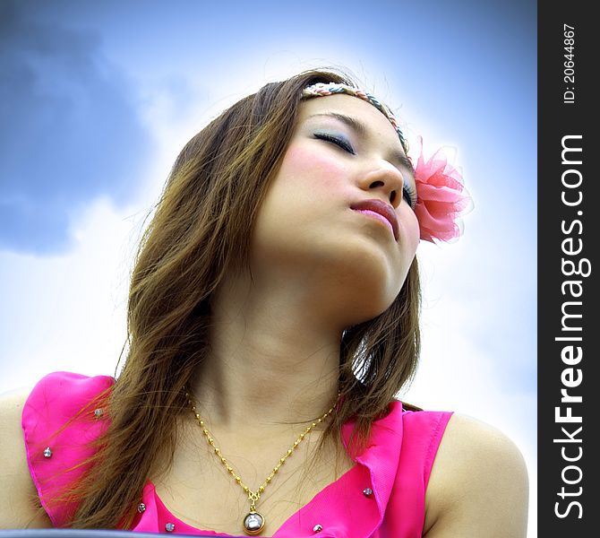 Beautiful Asian woman relaxing over the blue sky. Beautiful Asian woman relaxing over the blue sky.