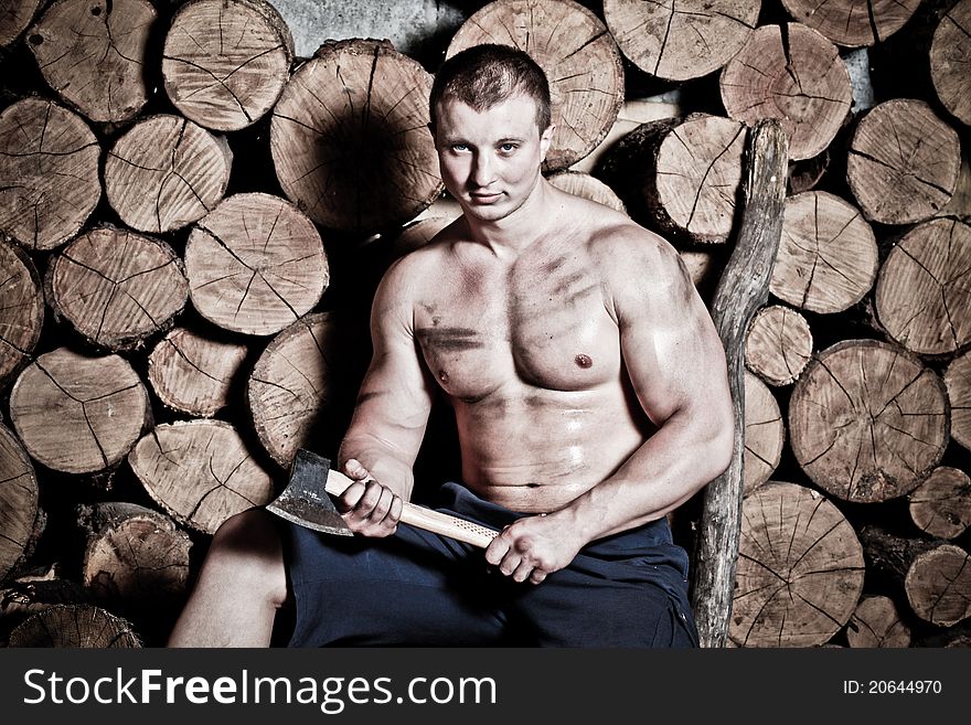 Young strong man with hatchet and a lot of woods