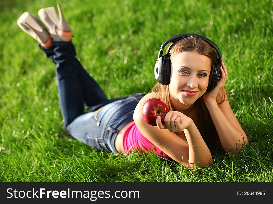 Woman with headphones listening music on the grass