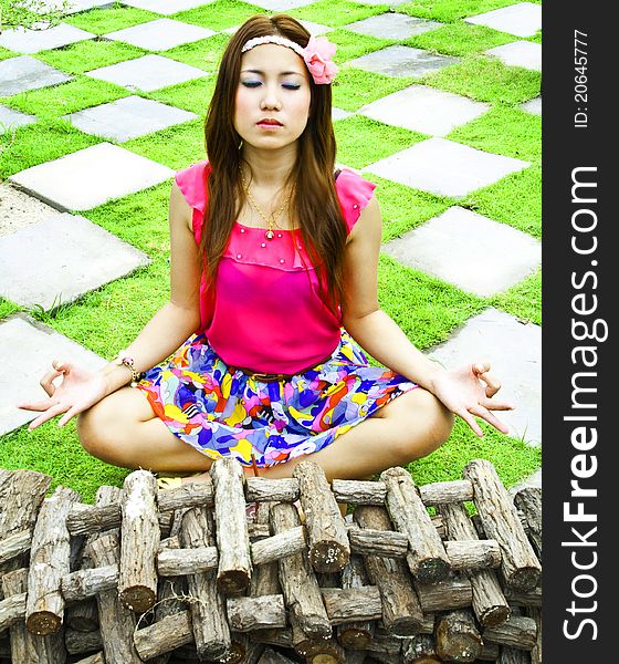 Beautiful Asian woman relaxing in the garden over over path and green grass. Beautiful Asian woman relaxing in the garden over over path and green grass.