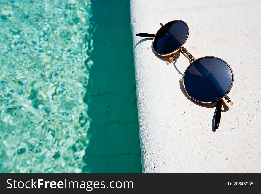 Black round sun glasses on pool boardin summer day