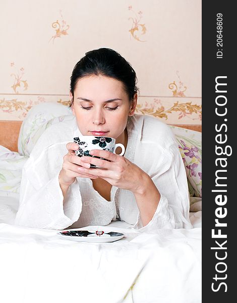 A young woman holding a cup of coffee at bedroom