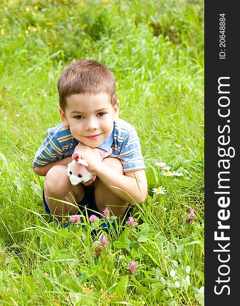 Happy little boy sitting on the grass in the park