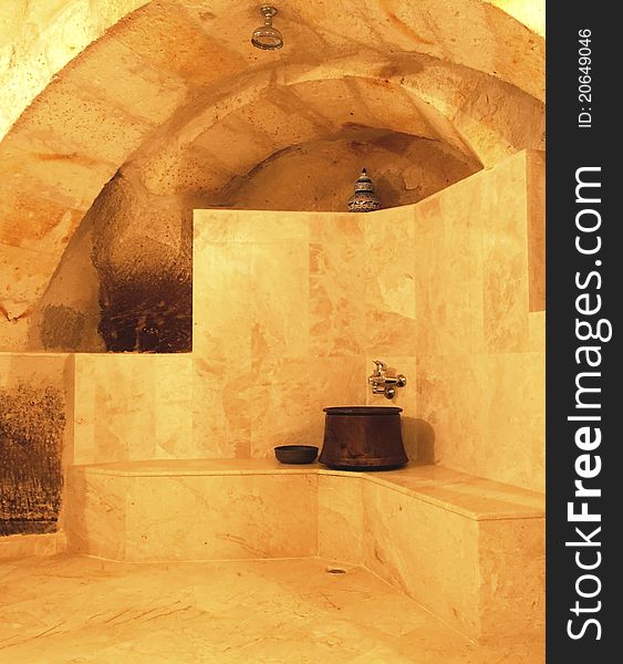 Renovation in a cave, shower room under aches archway, chrome taps, brass bucket, marble tiles, stepped feature, architectural detail, vertical, copy space and crop area. Renovation in a cave, shower room under aches archway, chrome taps, brass bucket, marble tiles, stepped feature, architectural detail, vertical, copy space and crop area