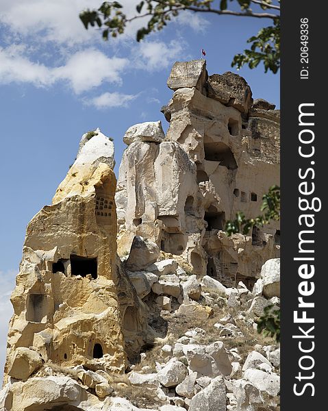 Close-up former cave home edge of Goreme Turkey, archaeological and architecture detailing, windows, doorways, rock formation of sandstone and limestone, framed by a tree, portrait, copy area, crop space