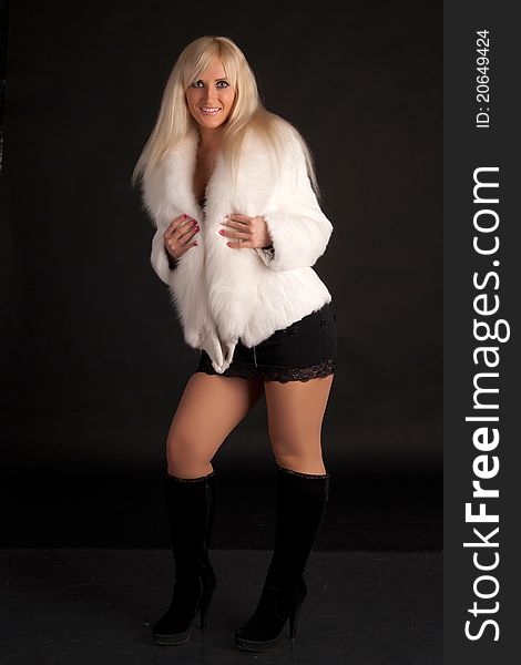 The glamour blonde in a warm white fur coat on a white background. The glamour blonde in a warm white fur coat on a white background