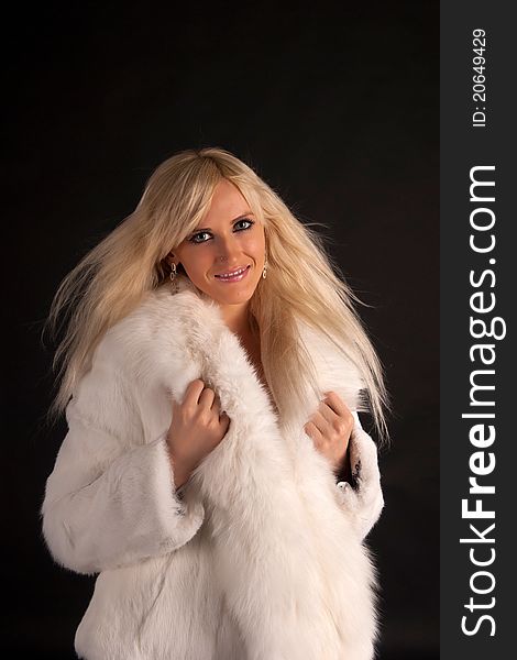 The glamour blonde in a warm white fur coat on a white background. The glamour blonde in a warm white fur coat on a white background