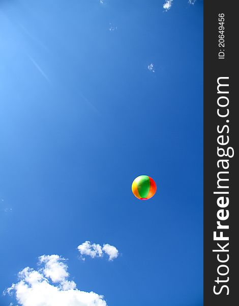 Beach ball thrown into a blue cloudy sky. Beach ball thrown into a blue cloudy sky