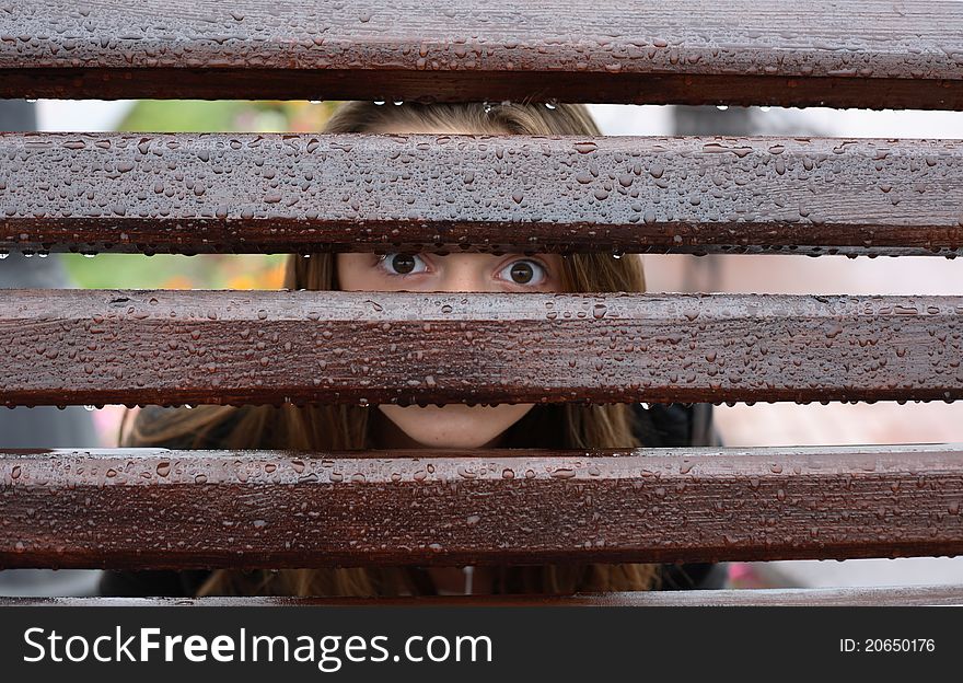 Teen girl looking through wet fence with water drops. Teen girl looking through wet fence with water drops