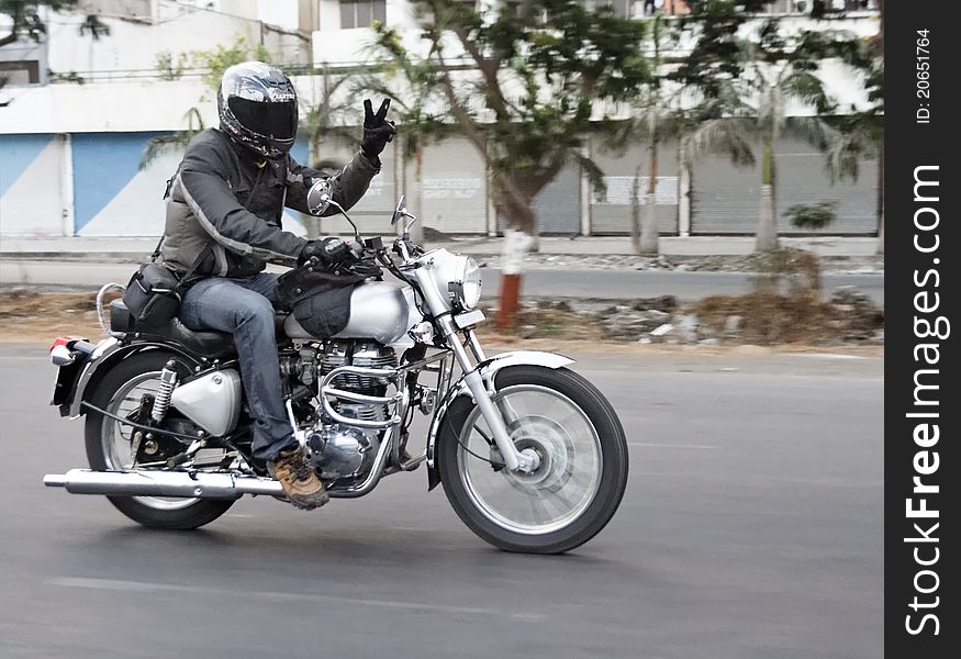 Motorbiker in motion doing peace sign