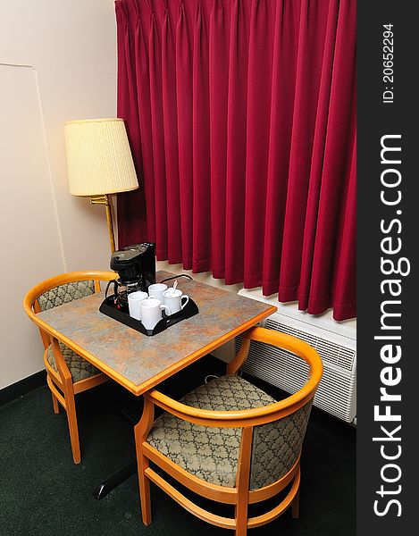 Chairs around table with coffee maker and cups. Chairs around table with coffee maker and cups.