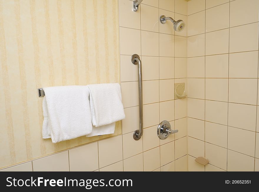Clean white towels hanging beside shower point in bathroom.
