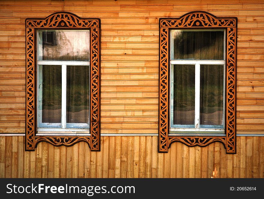 Two windows with wooden platbands. Ð¢raditional Russian decoration.