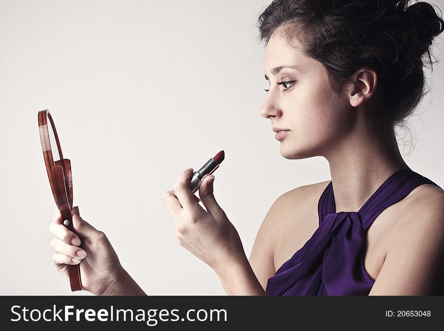 Beautiful woman putting on some lipstick. Beautiful woman putting on some lipstick