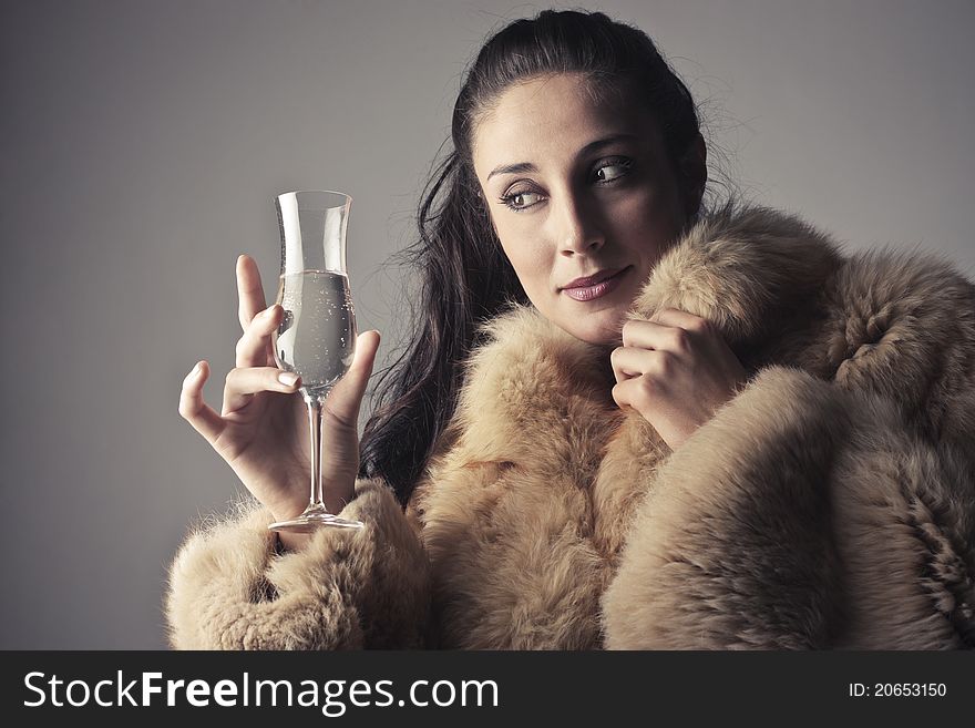 Beautiful woman wearing a fur and holding a glass of champagne