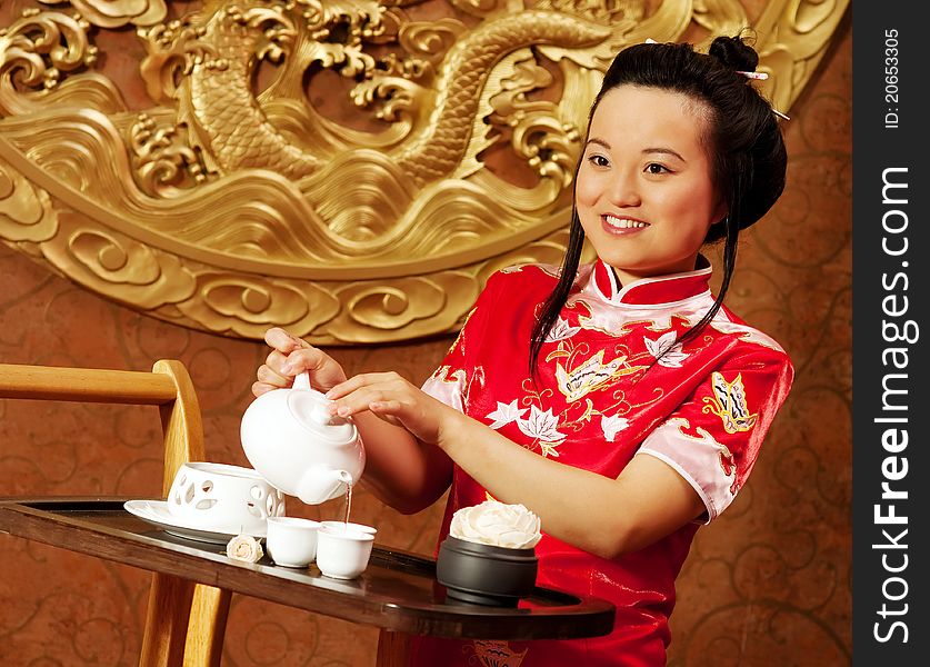 A Chinese girl in traditional dress making tea. A Chinese girl in traditional dress making tea