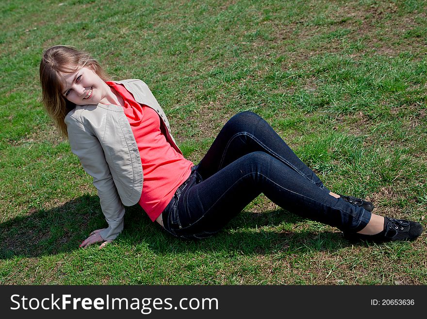 Smiling girl sitting in the park on the grass. Smiling girl sitting in the park on the grass