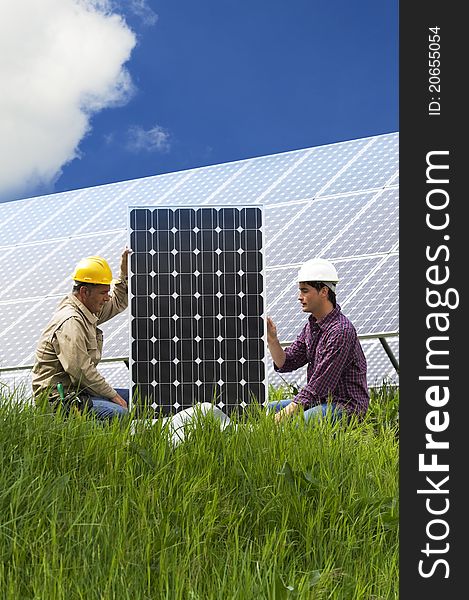 Technicians installing solar panels, low angle view