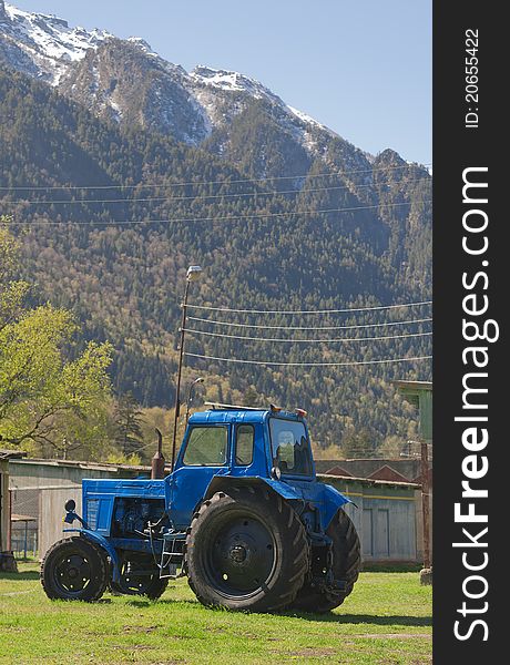 Blue tractor in the background of the mountains in spring