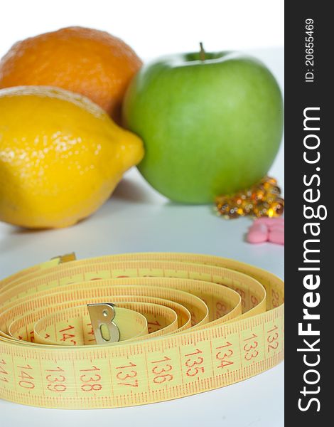 Tape measure, diet pills and fruits isolated on a white background