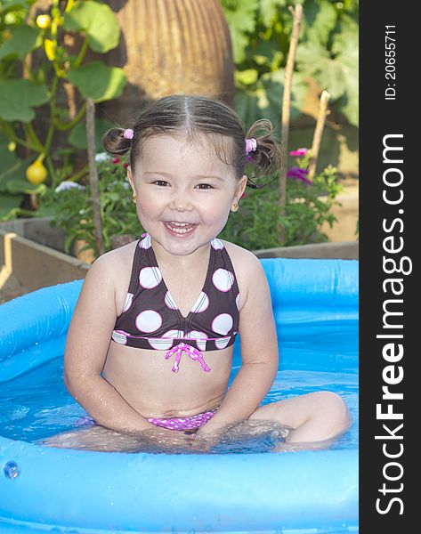 Happy little girl in a swimming pool in the garden