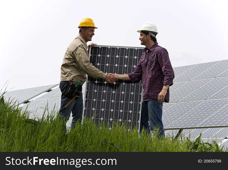 Technicians shaking hands while installing solar panels