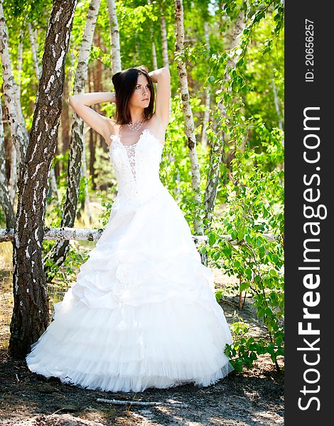 Bride with dark-brown hair posing in forest
