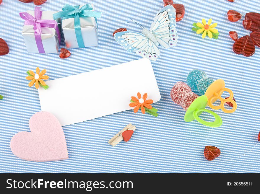 Background for the holiday newborn blue. Pacifiers - candy, red hearts, a butterfly net and a white card