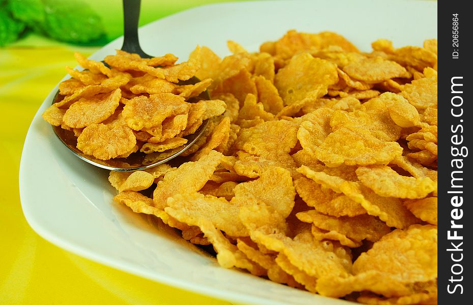 Cornflakes in bowl, on yellow background