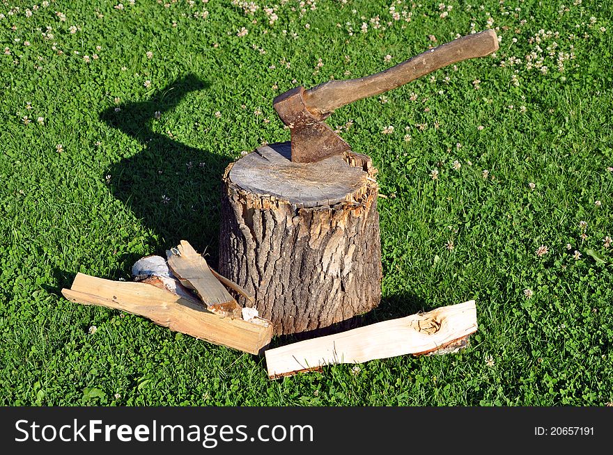 Firewood and axe on a green grass