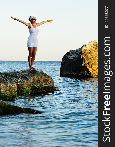 Smiling girl with arms raised towards the sky on sunny day on sunrise