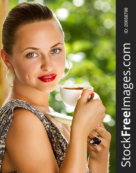 A young attractive woman with a cup of coffe near the window