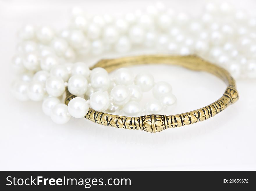 Set of brass bracelet and a lace of imitation pearls on white. Set of brass bracelet and a lace of imitation pearls on white.