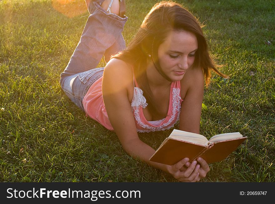 Woman laying down and reading in the twilight of the day. Woman laying down and reading in the twilight of the day.