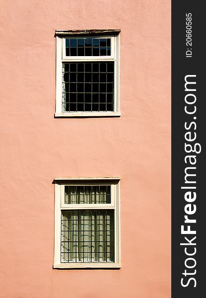 Two old style windows on a pink wall