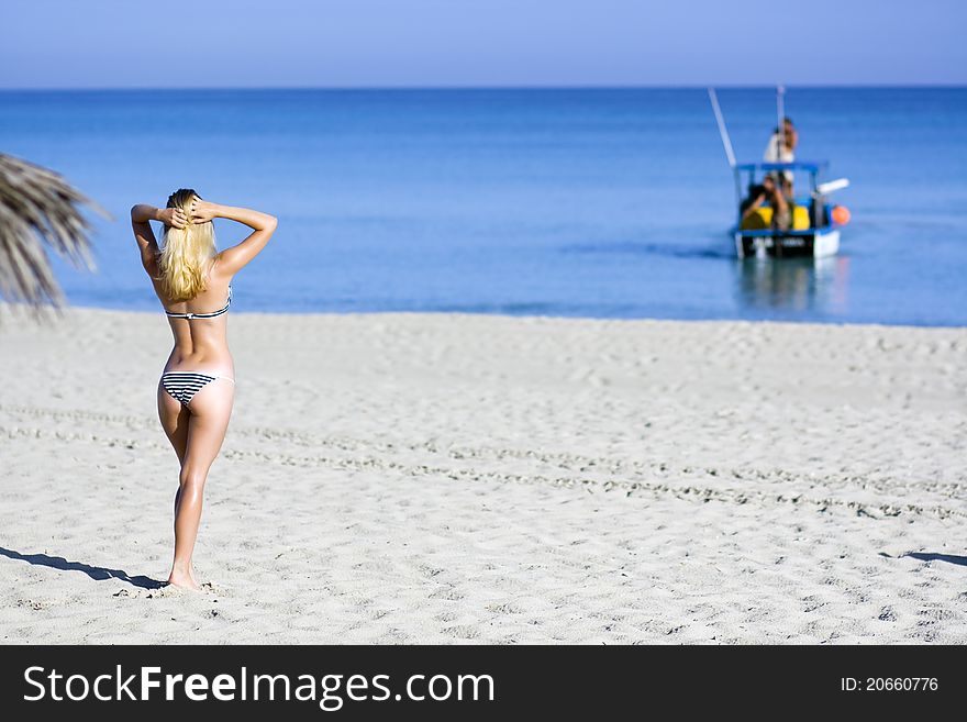 Pretty woman in stripped bikini is looking at the sea. Pretty woman in stripped bikini is looking at the sea