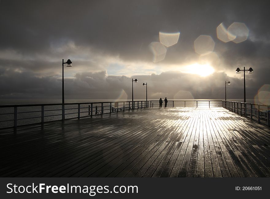 People on a pier during sunset, after the rain. People on a pier during sunset, after the rain