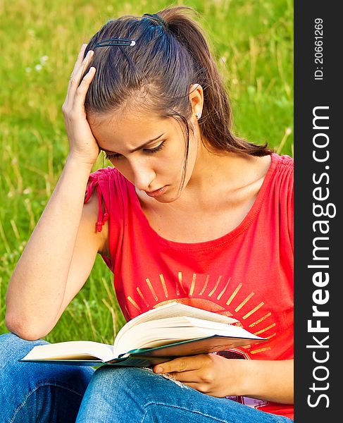 Portrait of a young beautiful woman reading a book in the park. Portrait of a young beautiful woman reading a book in the park