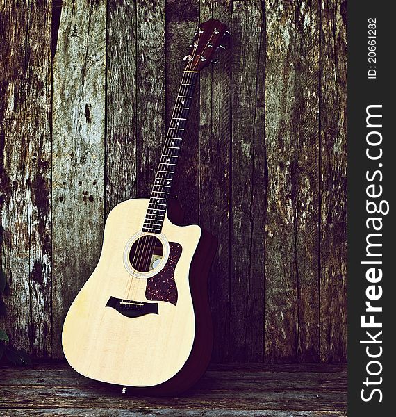 Richly toned image of a classical guitar on a grunge wood backdrop with copy space. Richly toned image of a classical guitar on a grunge wood backdrop with copy space.