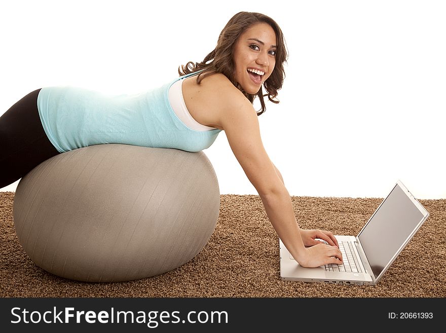 A woman laying on her exercise ball working on the computer. A woman laying on her exercise ball working on the computer.