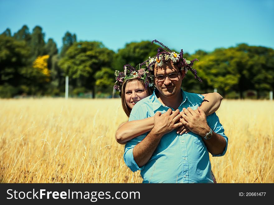 Middle aged couple with flowers crowns huging in a field