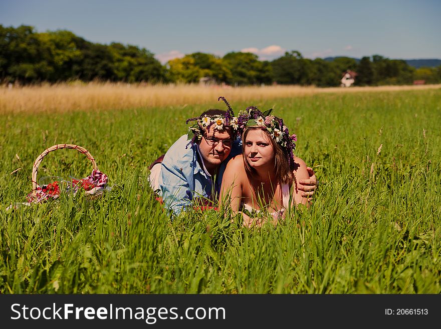 Happy middle aged couple with flowers crown resting on a grass. Happy middle aged couple with flowers crown resting on a grass