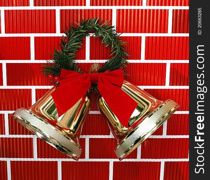 Gold Christmas Holiday Bells with Red Bow and Garland isolated on red brickwall background